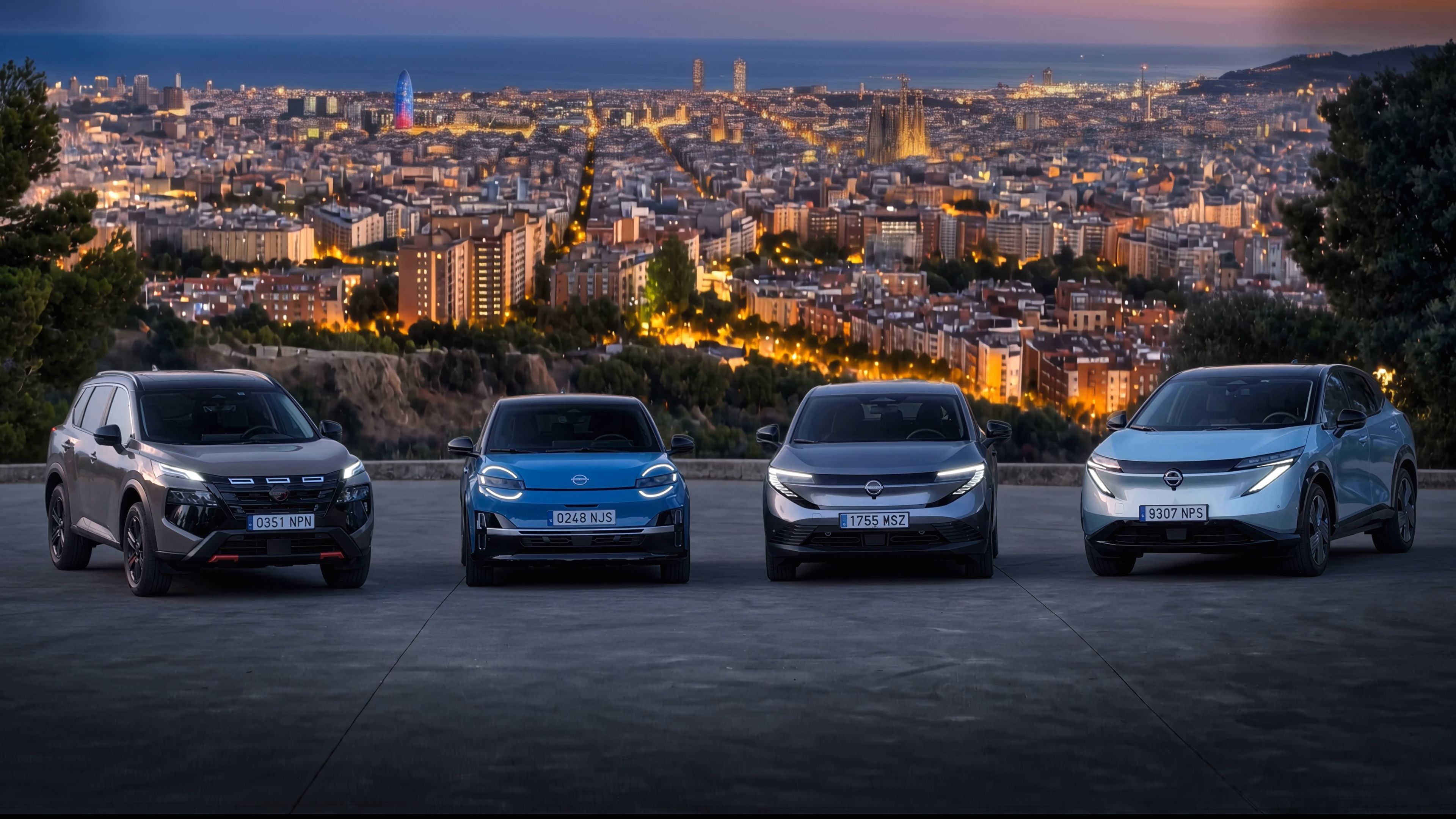Four Nissan electrified vehicles parked in front of a city skyline at dusk